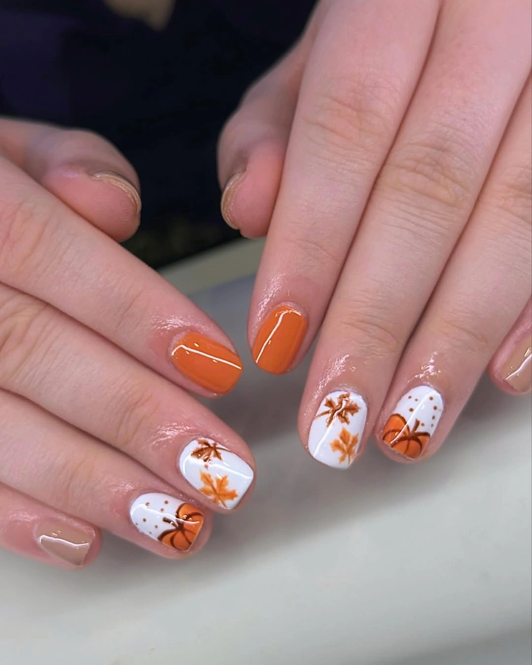 Short square orange nails with white pumpkin illustrations