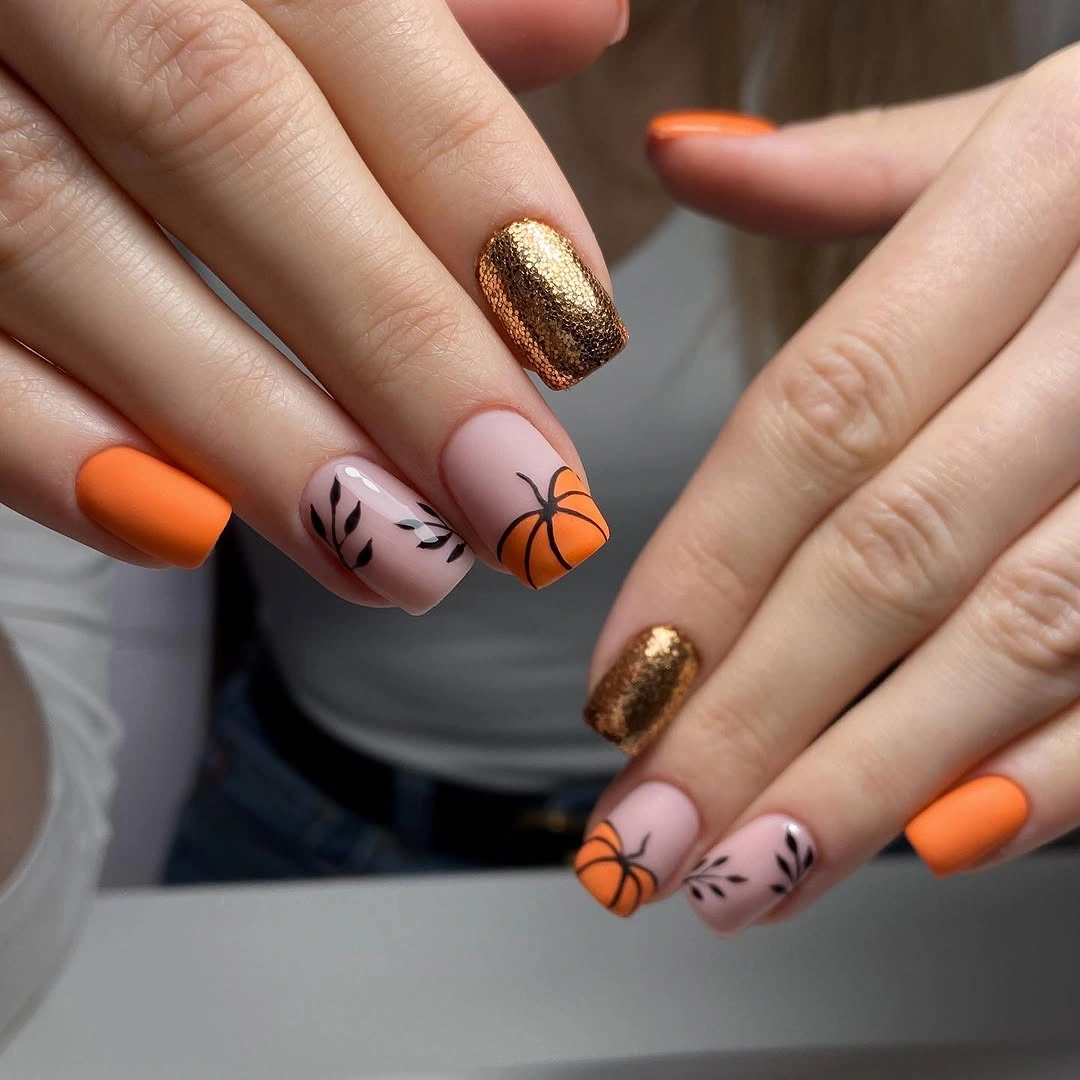 Medium almond orange nails with gold glitter and pumpkin art