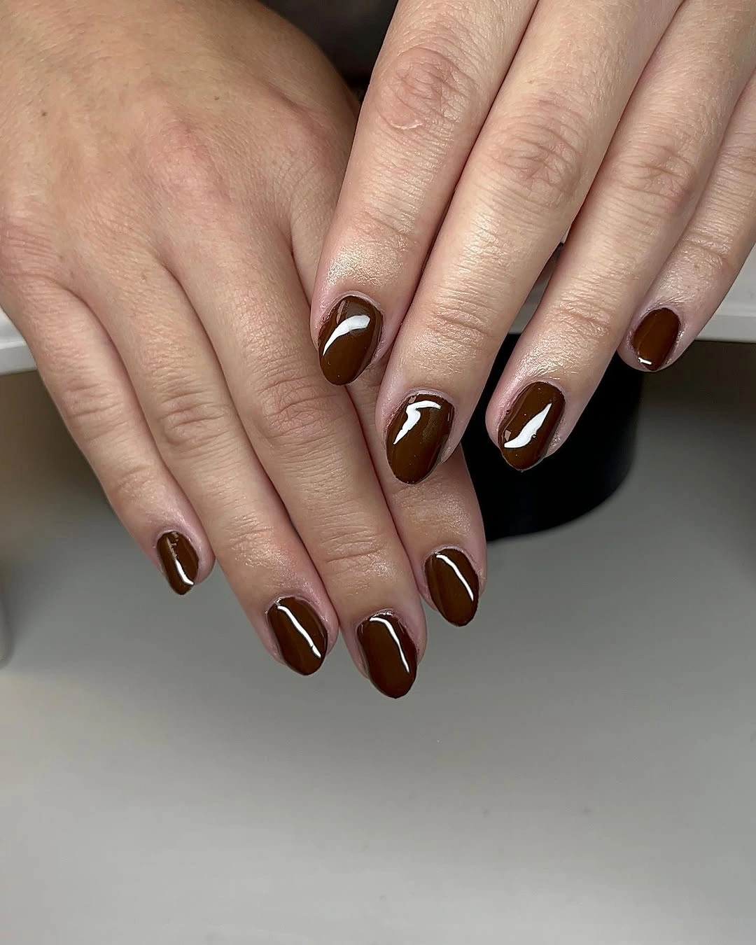short glossy brown almond nails with a pale swirl