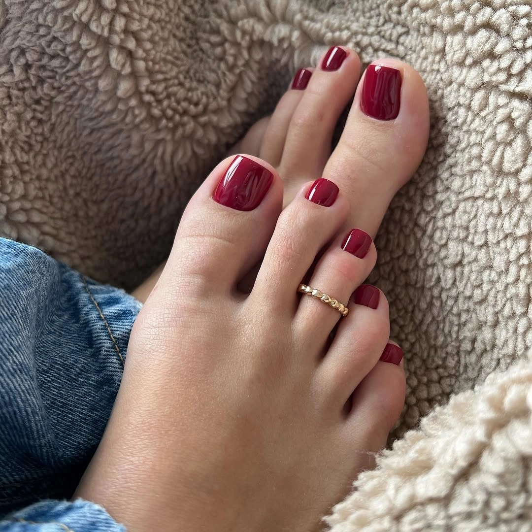 Glossy cherry red polish on short square toes