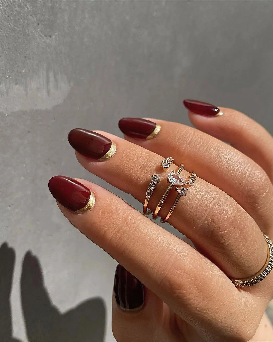 deep wine almond nails with a fine gold edge