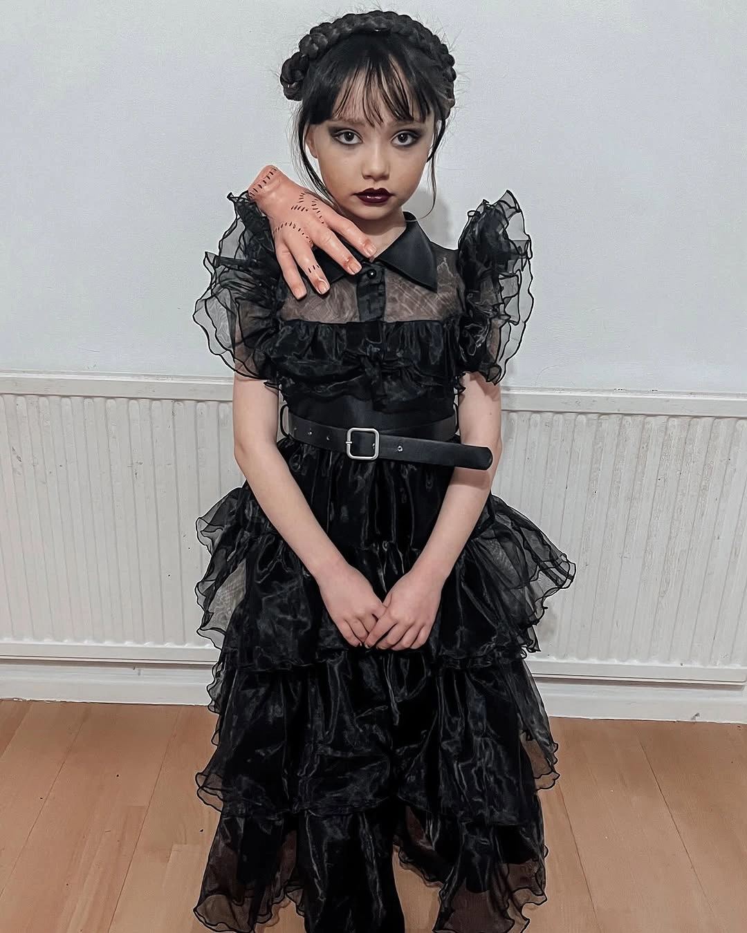 black outfit with defined waist with ruffled shoulders and layered skirt