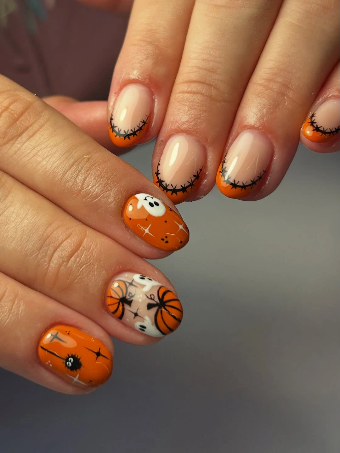Short rounded orange nails with webs pumpkins ghosts and stars