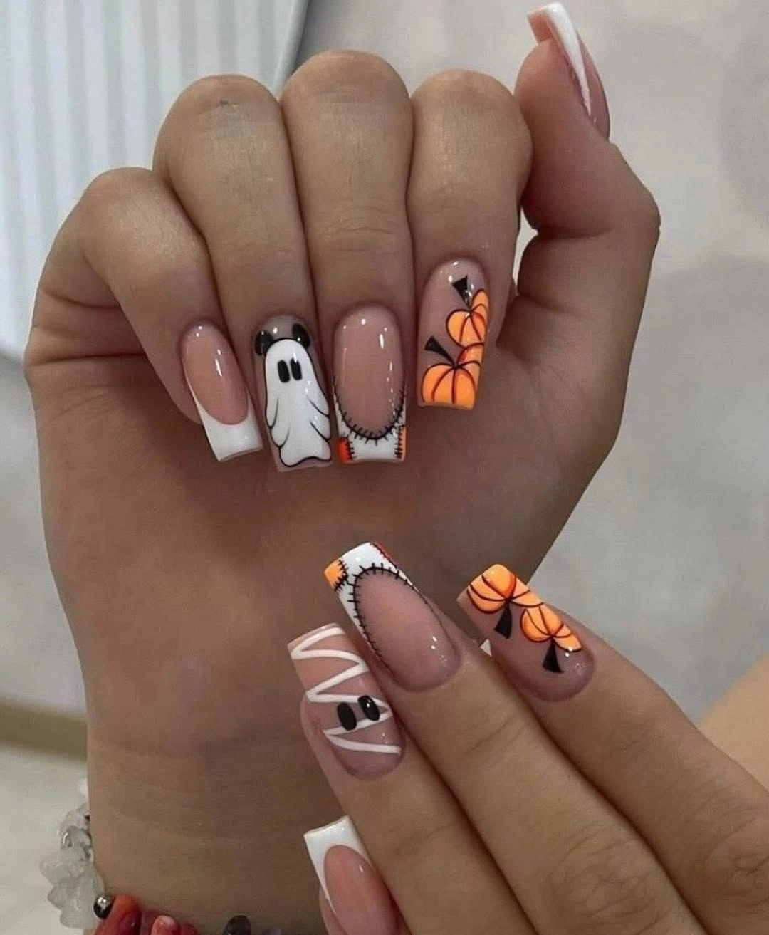 Medium almond pale pink nails with orange black spooky details