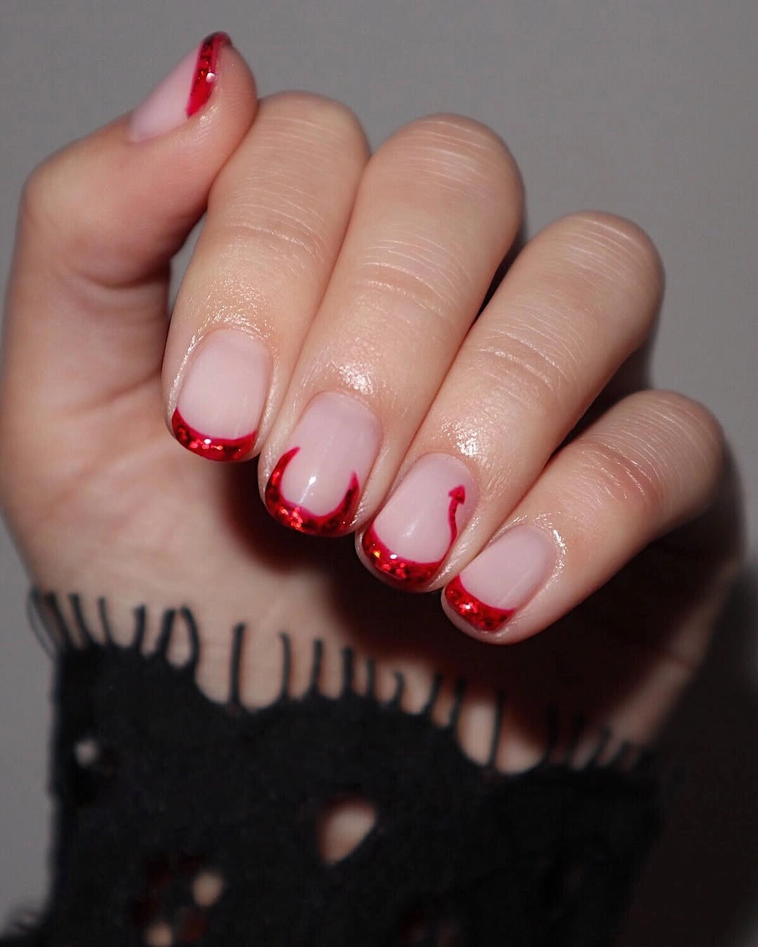 Short rounded pale pink nails with red curved edges
