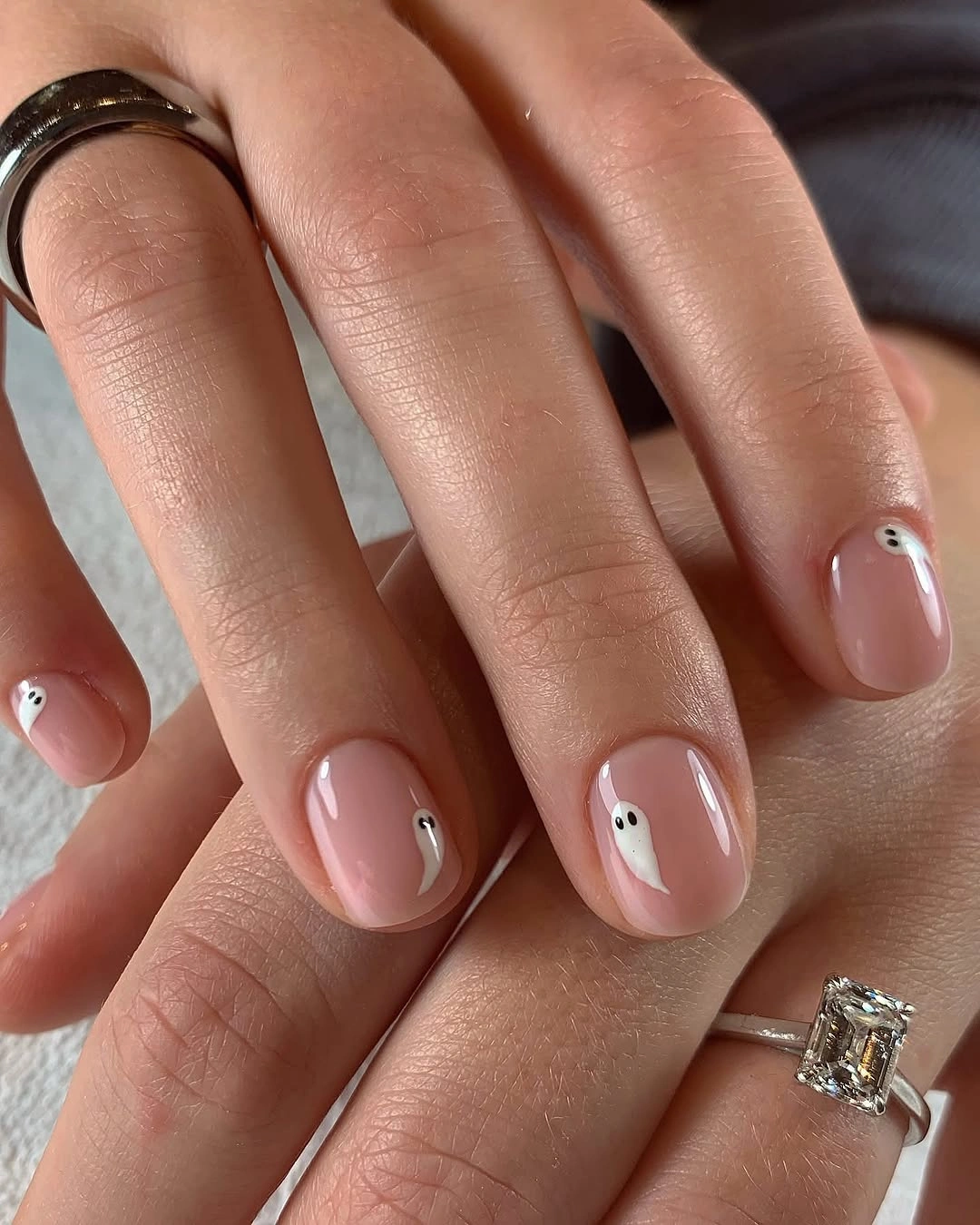 Short oval pale pink nails with tiny white ghost faces