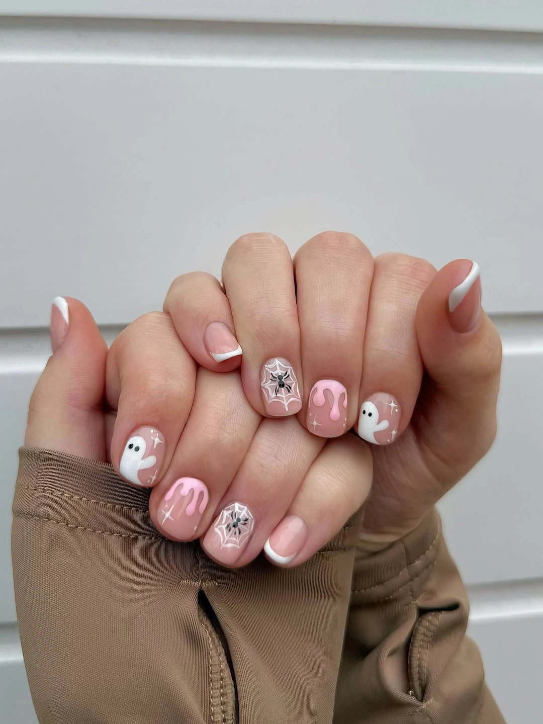 Short oval pale pink nails with white ghosts and silver details