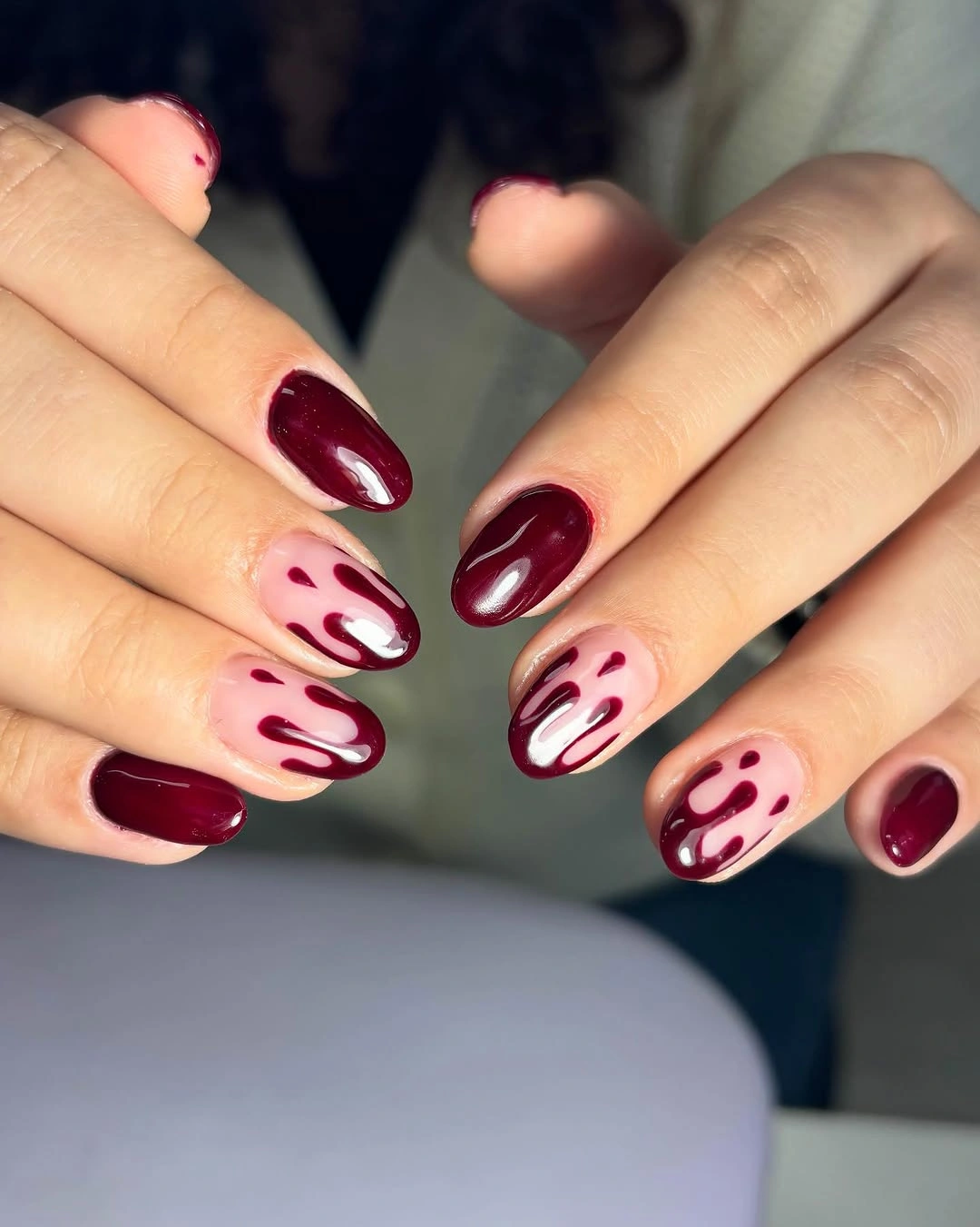 Short oval burgundy nails with pale panels and red drips