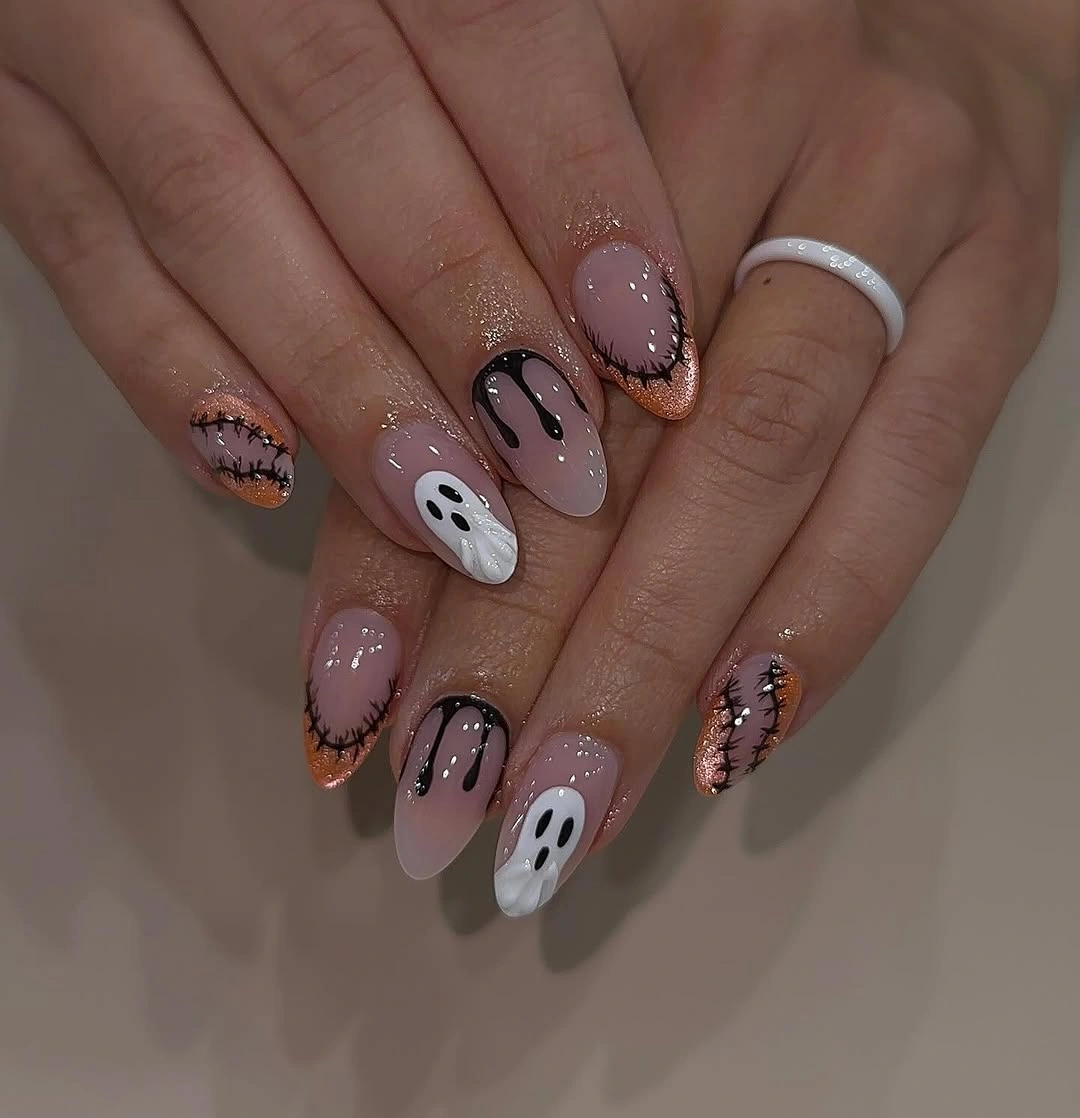 Medium almond pale pink nails with black orange spooky linework