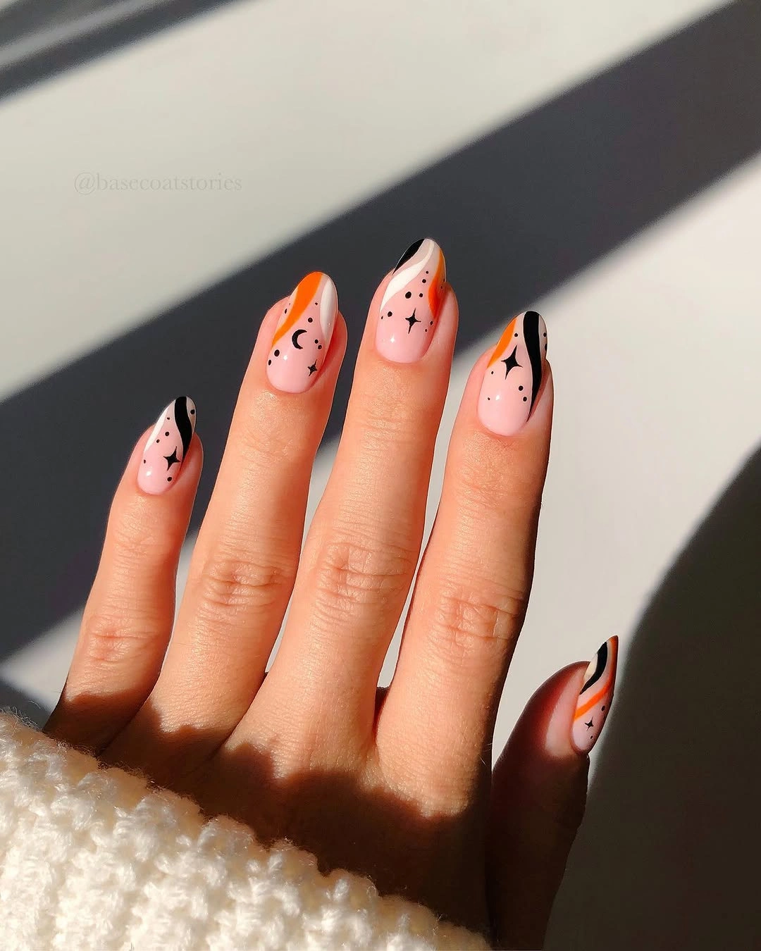 Medium almond pale pink nails with black orange curved tips