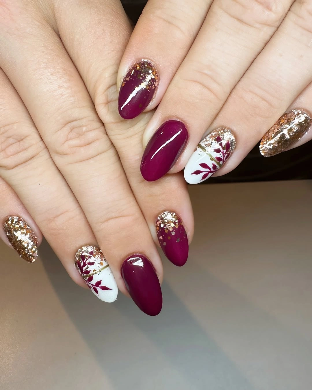 Berry almond nails with white florals and gold glitter