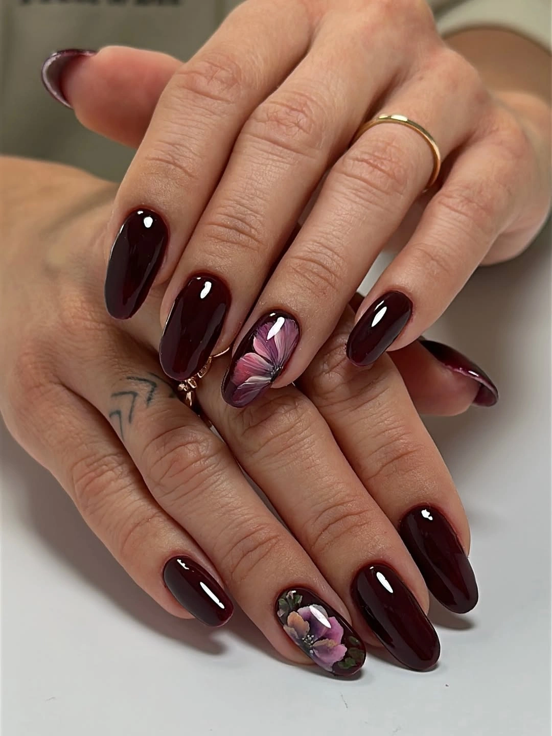 Long glossy maroon almond nails with open floral accents