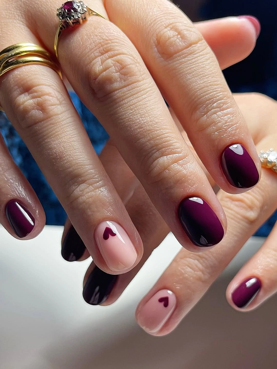 Short burgundy nails with tiny heart accent motifs