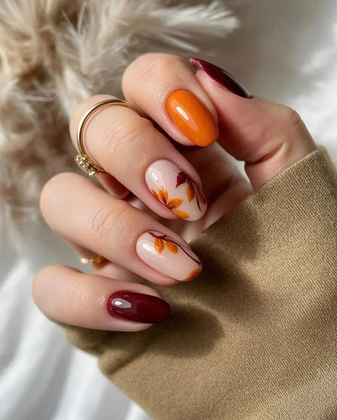 Burgundy almond nails with orange and leafy pale accents