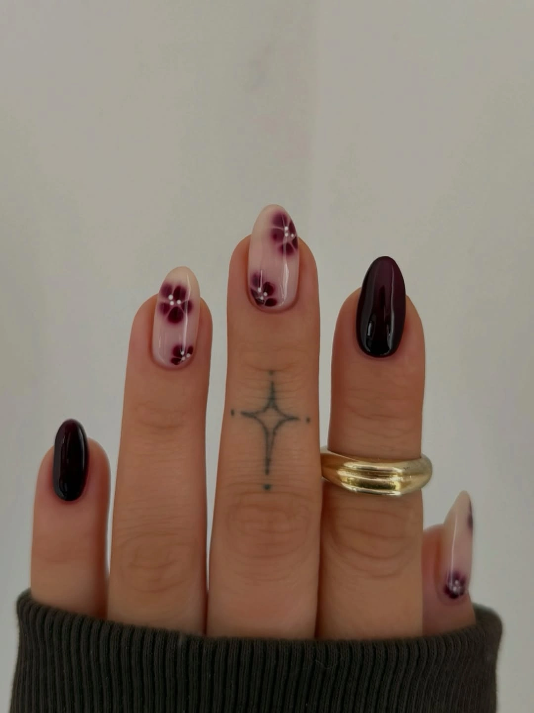 Dark maroon rounded nails with tiny pale dot clusters
