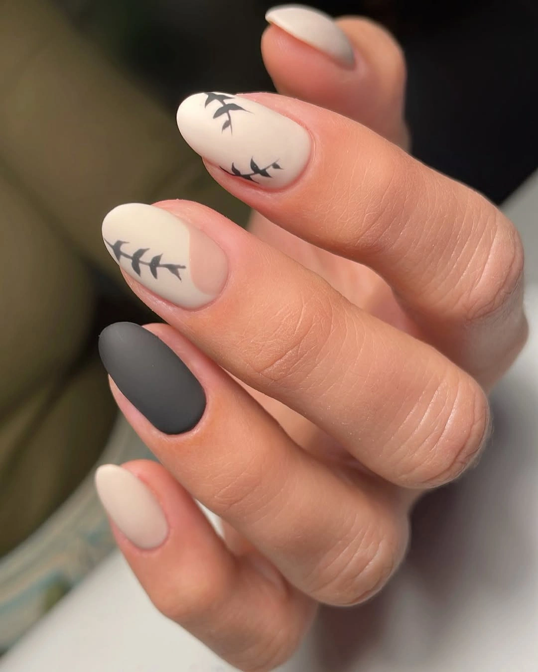 Cream almond nails with black twig accents and charcoal nail