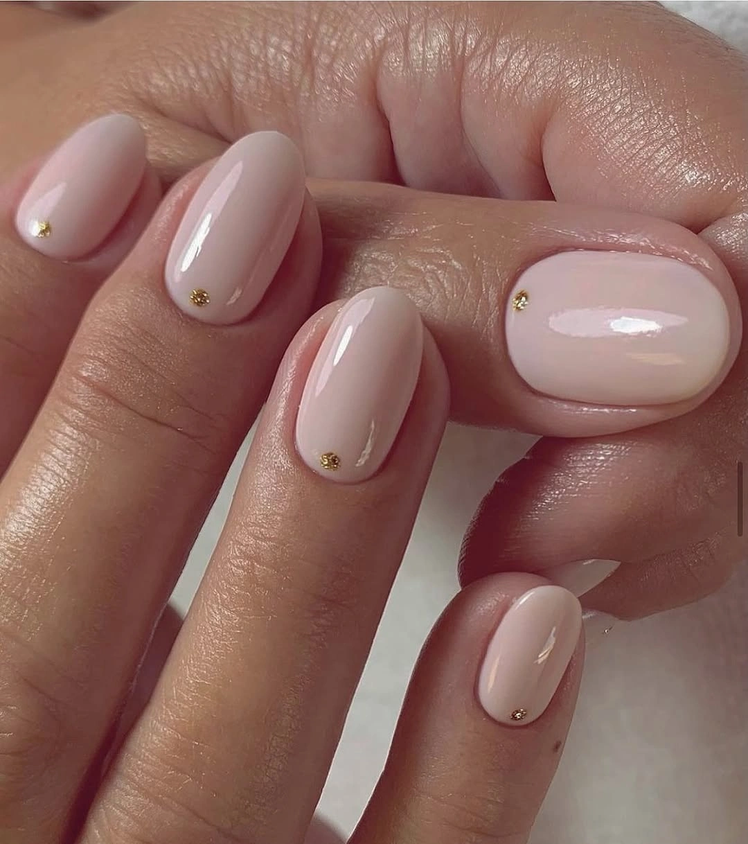 Short rounded nude pink nails with tiny cuticle dots