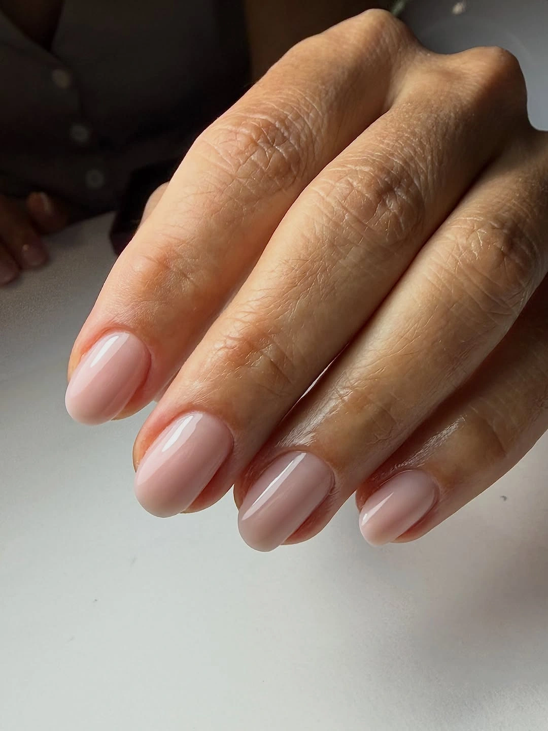 Short rounded nails in a clean glossy pale pink nude