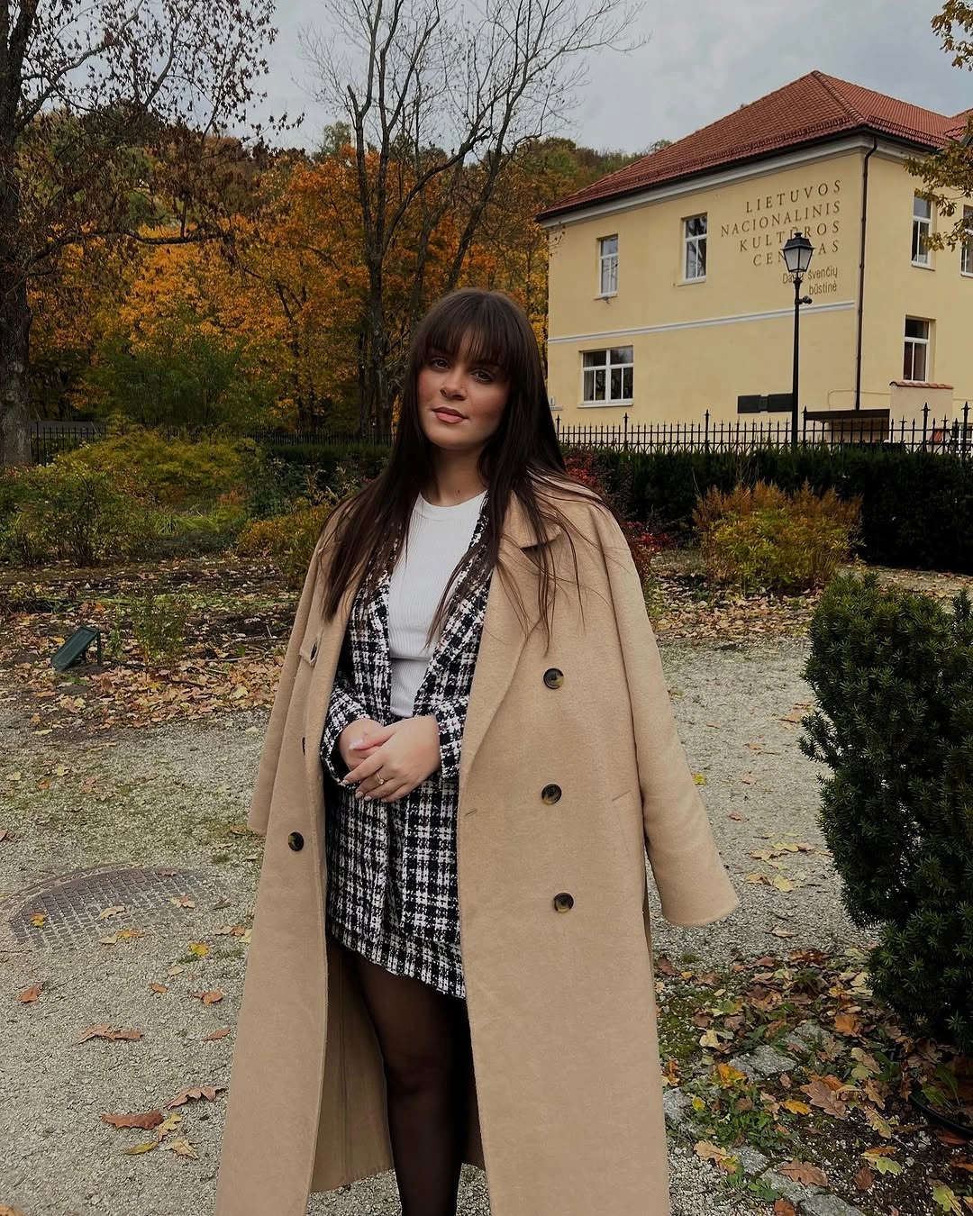 camel outfit with long coat over short checked layer with tights