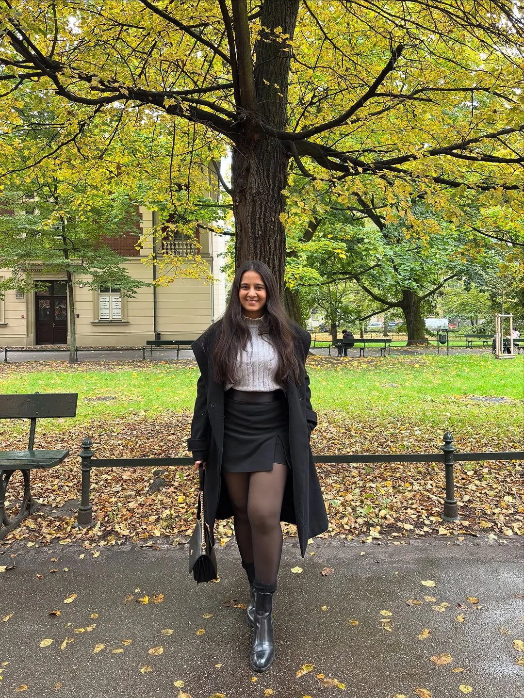 black outfit with long coat over short skirt with tights and ankle boots