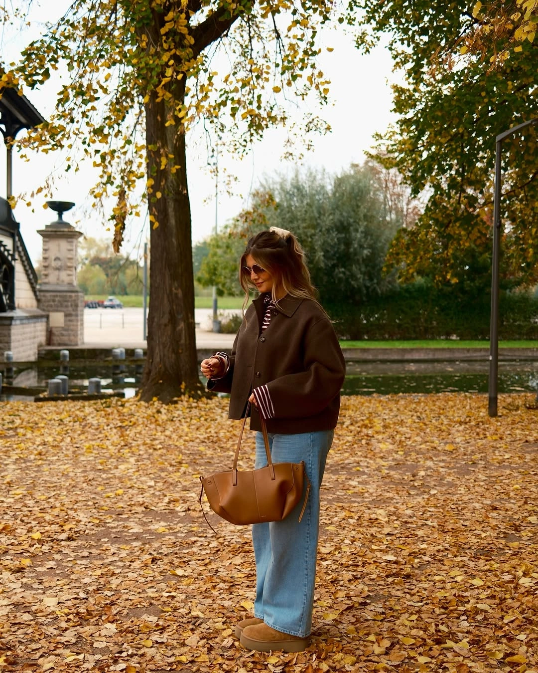 brown outfit with short jacket over striped knit and relaxed denim
