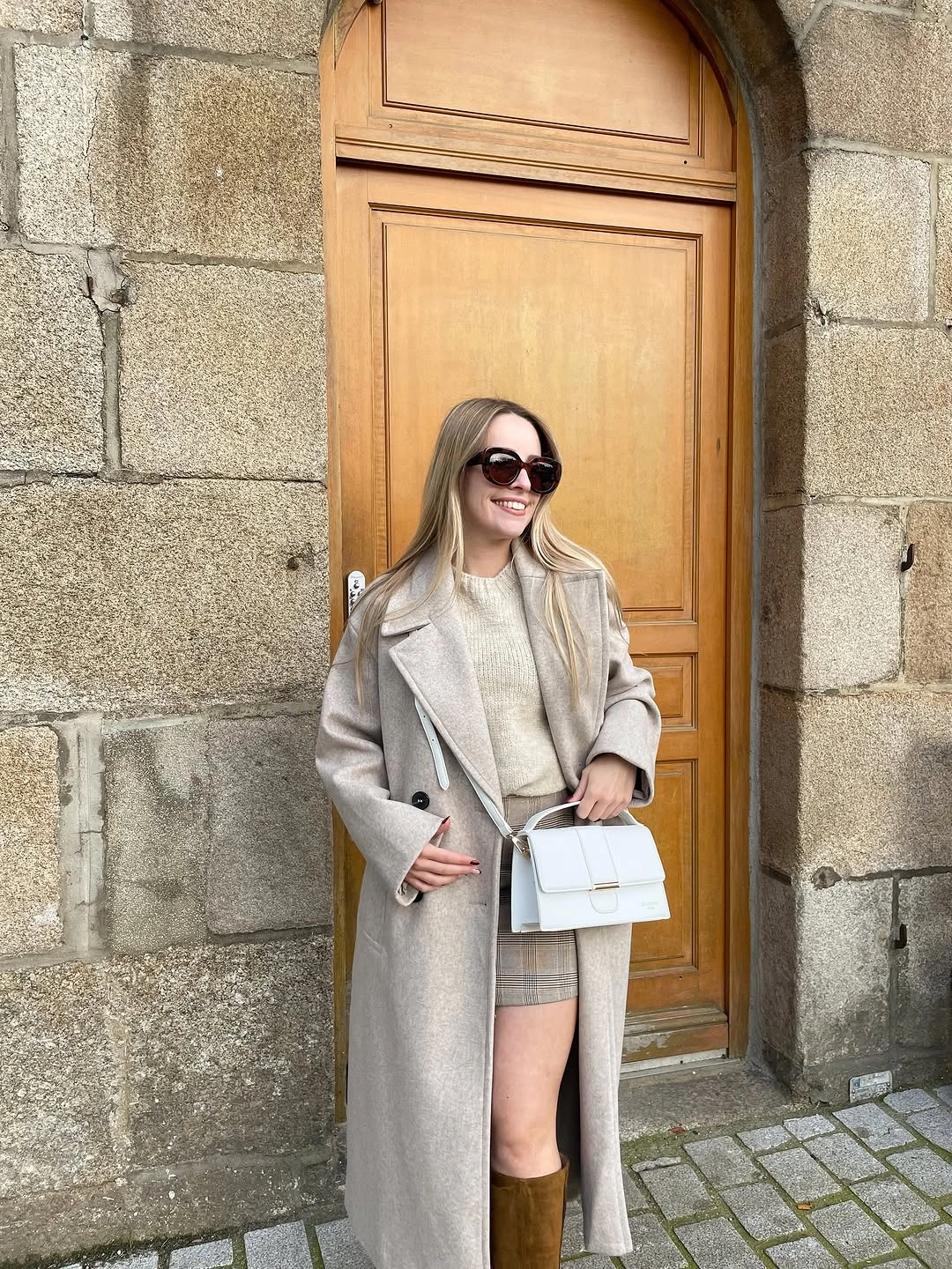 light gray outfit with long pale coat over short neutral base with tall boots