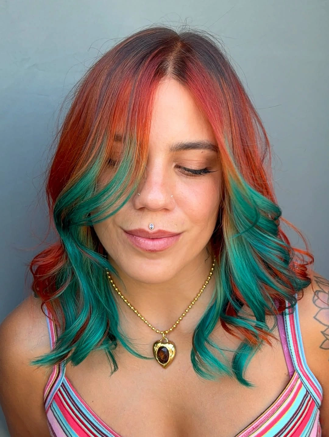 copper red shoulder-length layered waves with center part with red-and-teal contrast