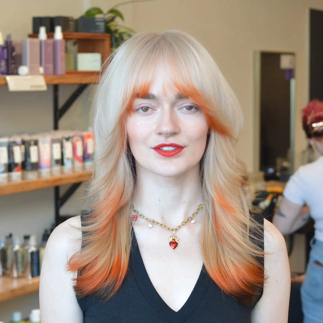 pale blonde medium-long layered cut with fringe with orange internal streaks