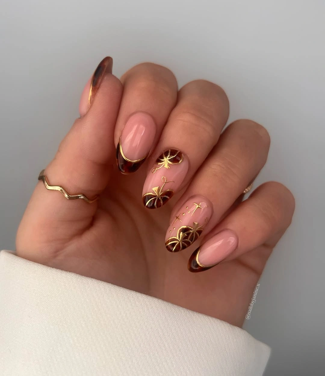 pale pink medium almond nails with gold floral bursts