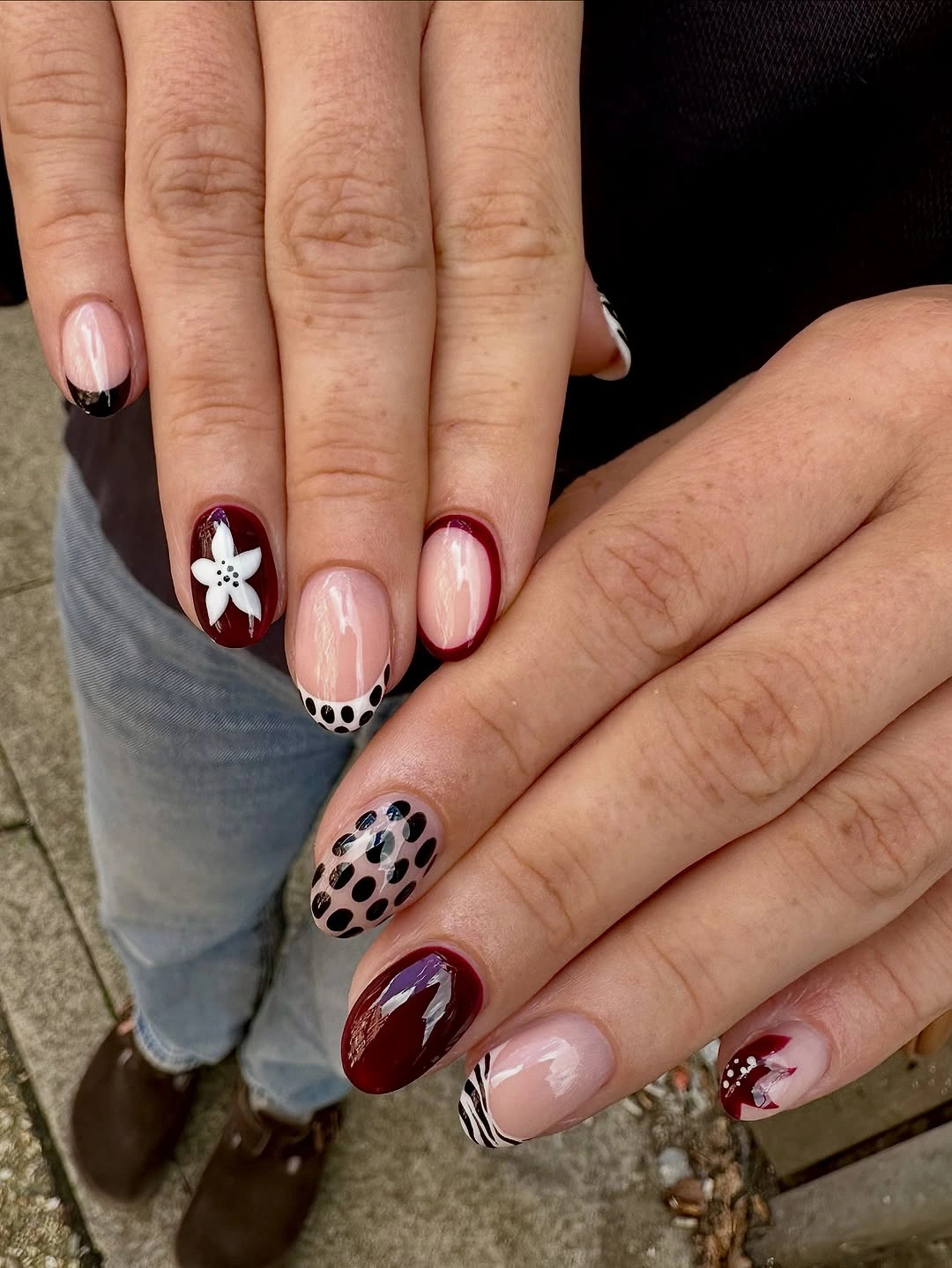 burgundy short rounded nails with flower, spots, curved stripes