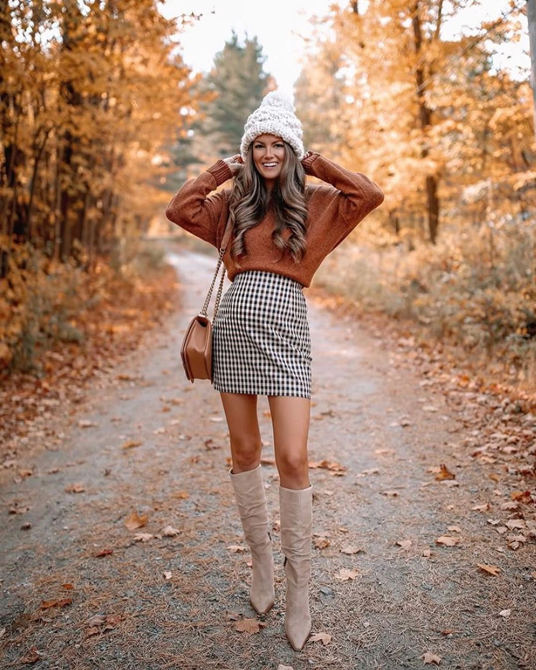 rust outfit with relaxed sweater over short checked skirt with tall boots