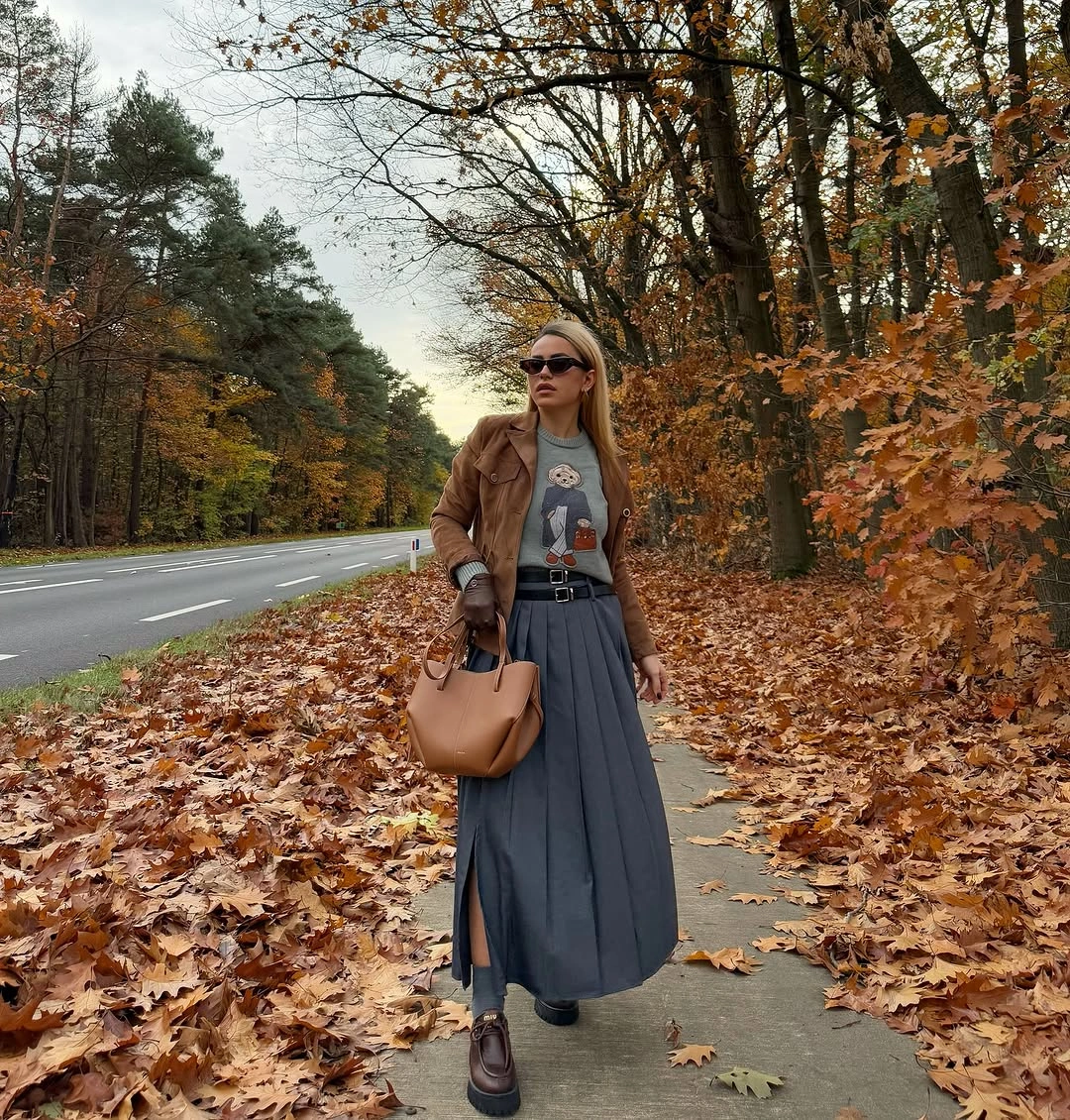 brown outfit with short jacket over graphic tee and long pleated skirt
