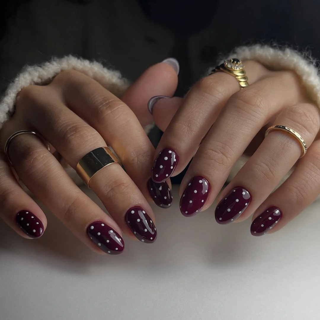 Deep plum almond nails with small pale dots