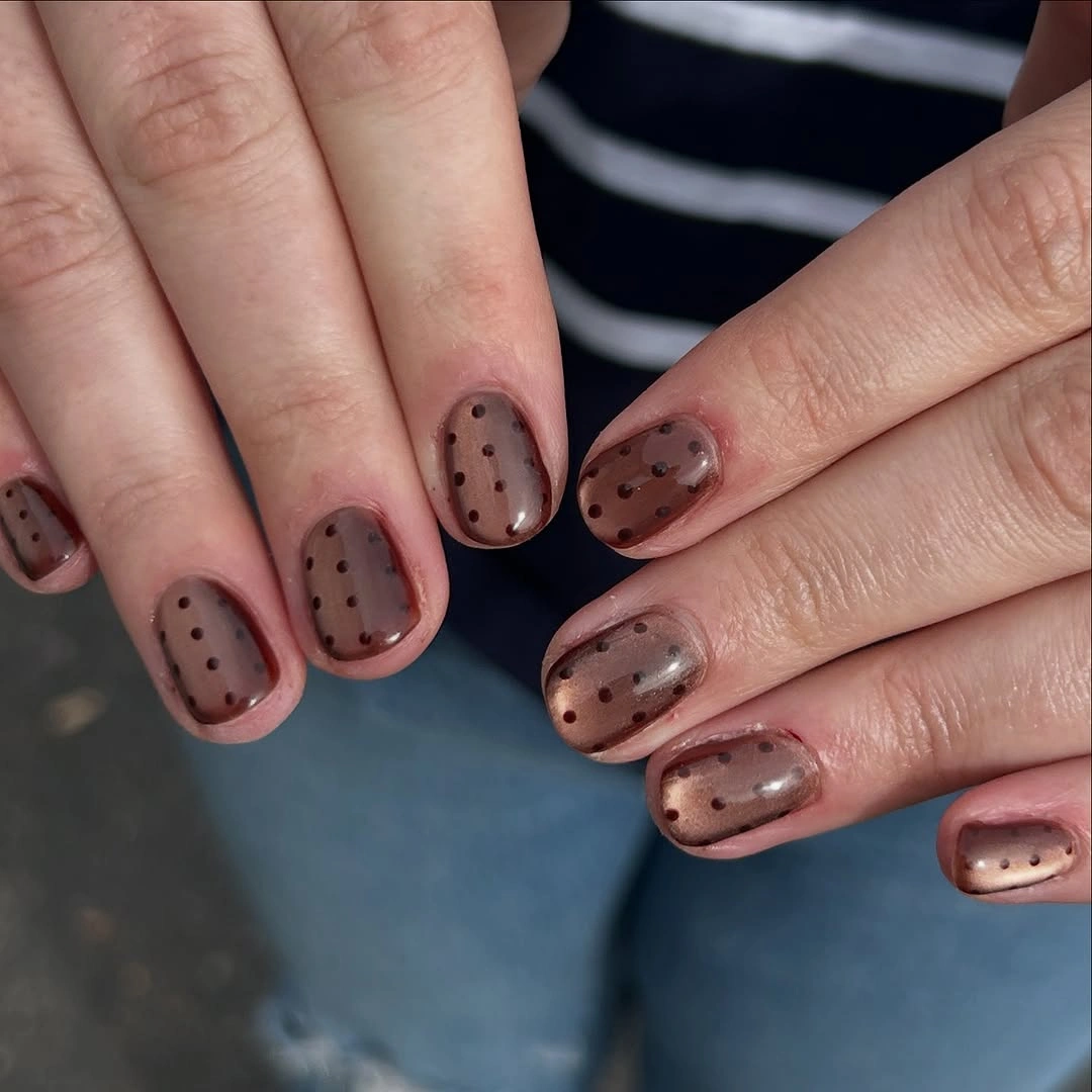 Short rounded brown nails with small dark dots