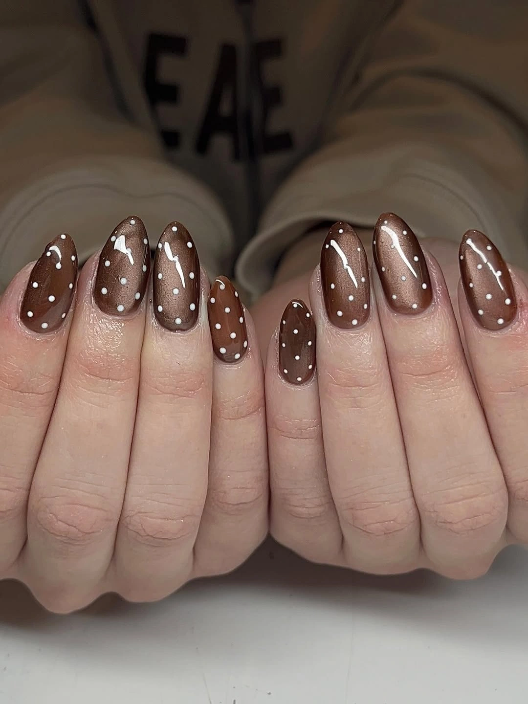 Glossy chocolate almond nails with dense white dots