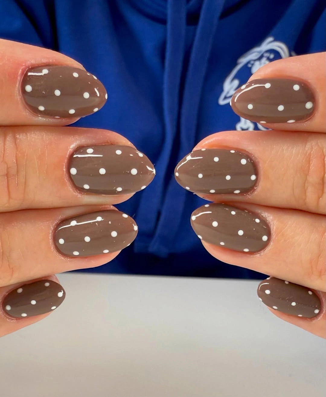 Glossy taupe brown oval nails with even white dots