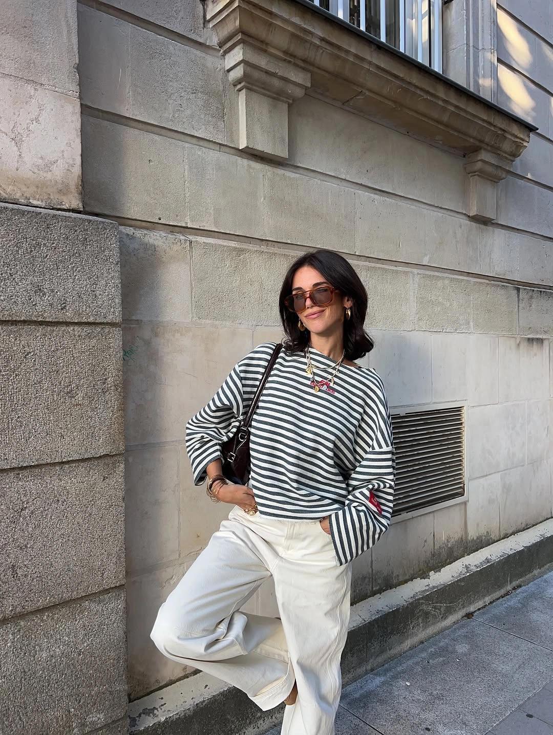Striped top with loose white trousers and dark accessories