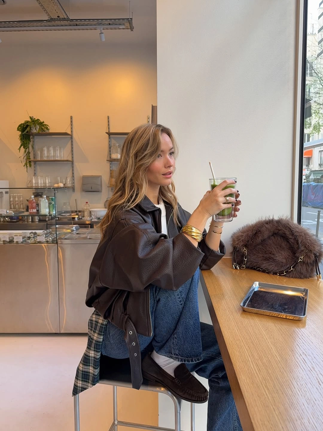Brown jacket layered over denim with a large bag