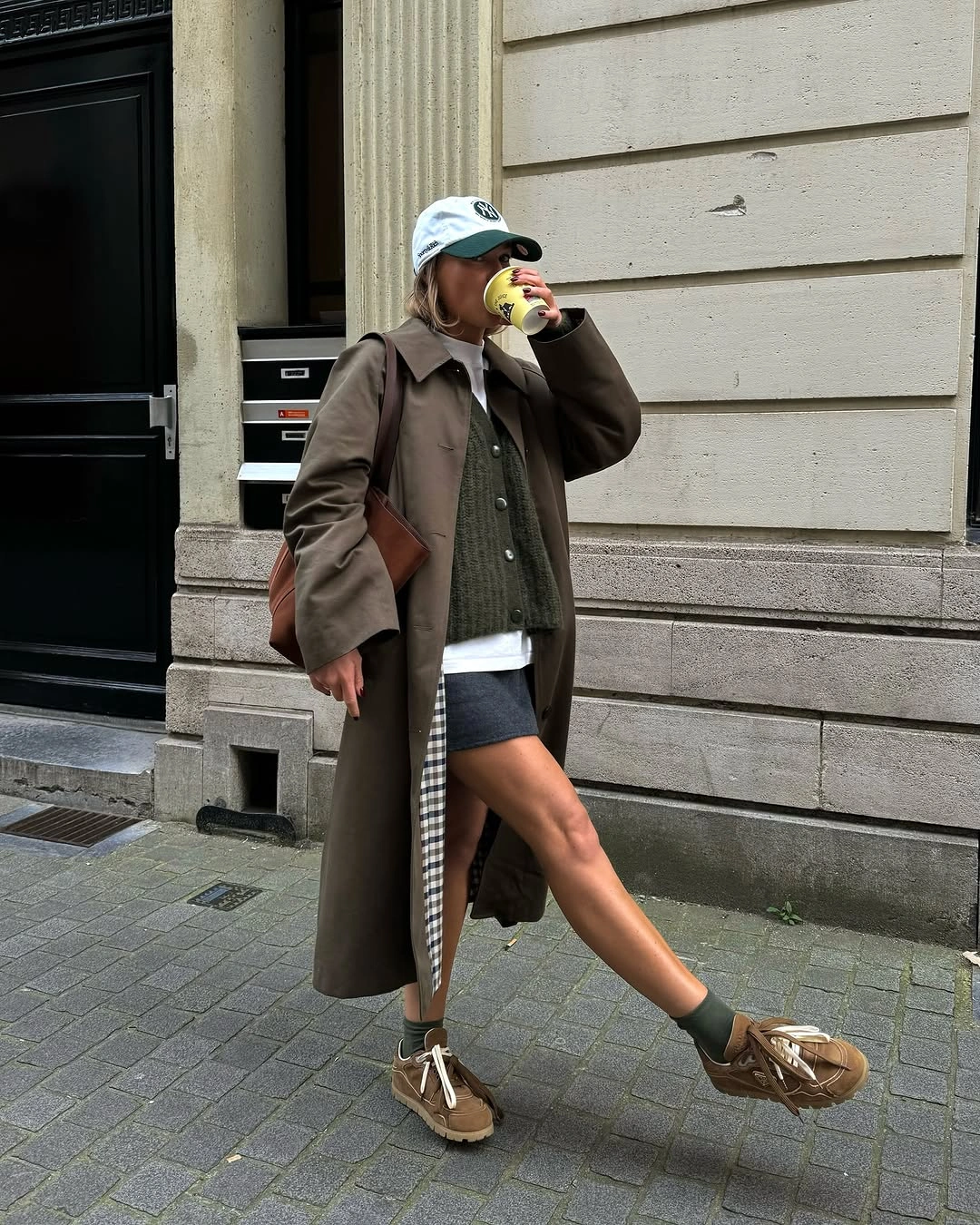 Long olive coat with denim shorts and tan lace-up shoes