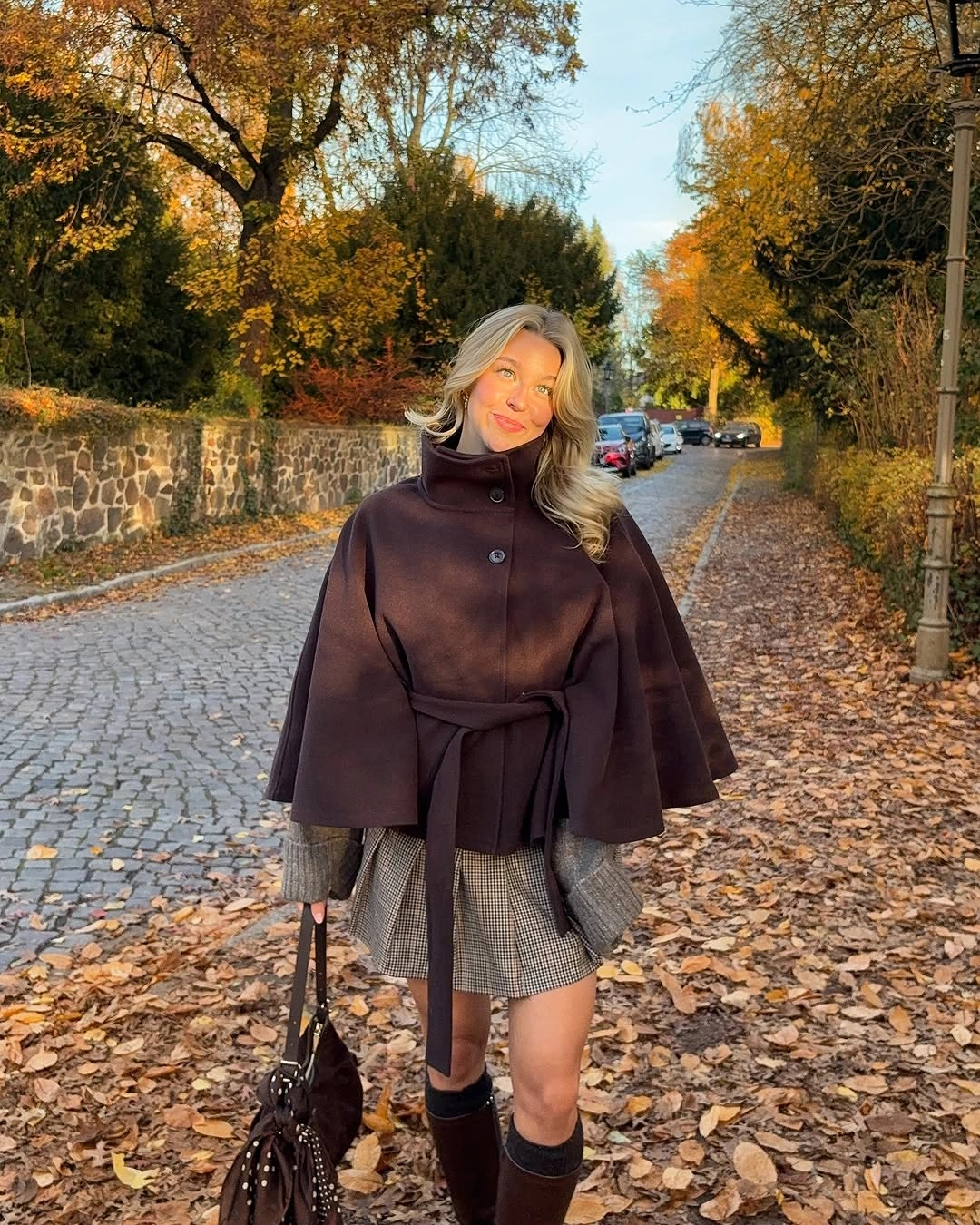 Belted brown cape with plaid mini skirt and tall boots