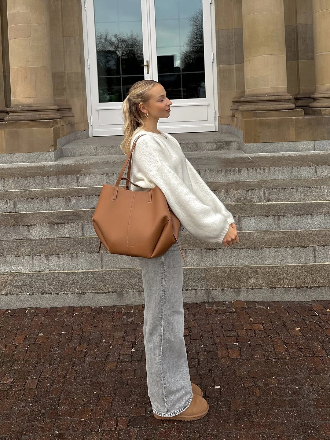 Cream sweater with wide gray jeans and tan tote