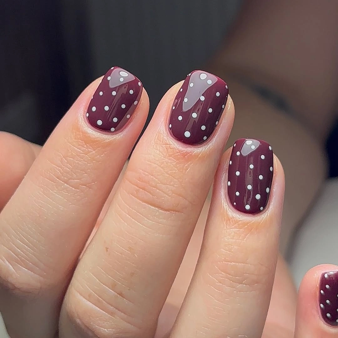 short rounded plum nails with an even white dot pattern