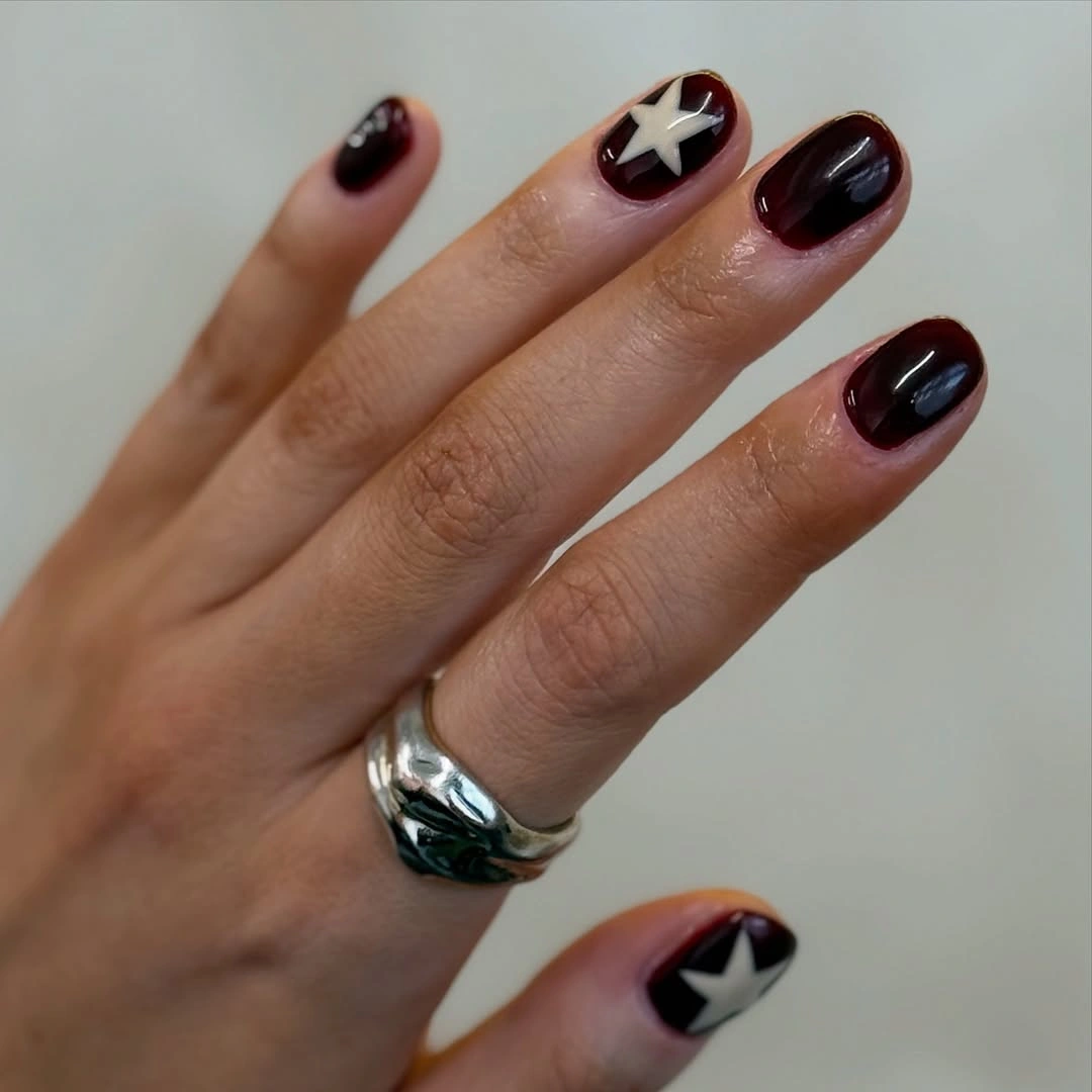 short rounded dark burgundy nails with white star accents