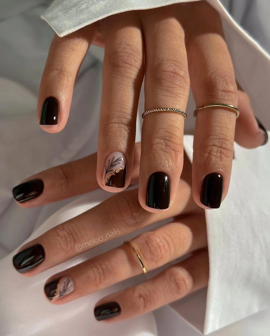 short square black nails with one pale feather-like accent