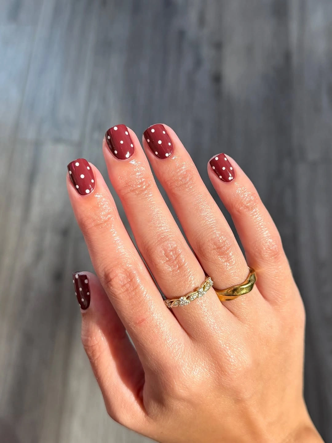 short rounded burgundy nails with repeated white dots