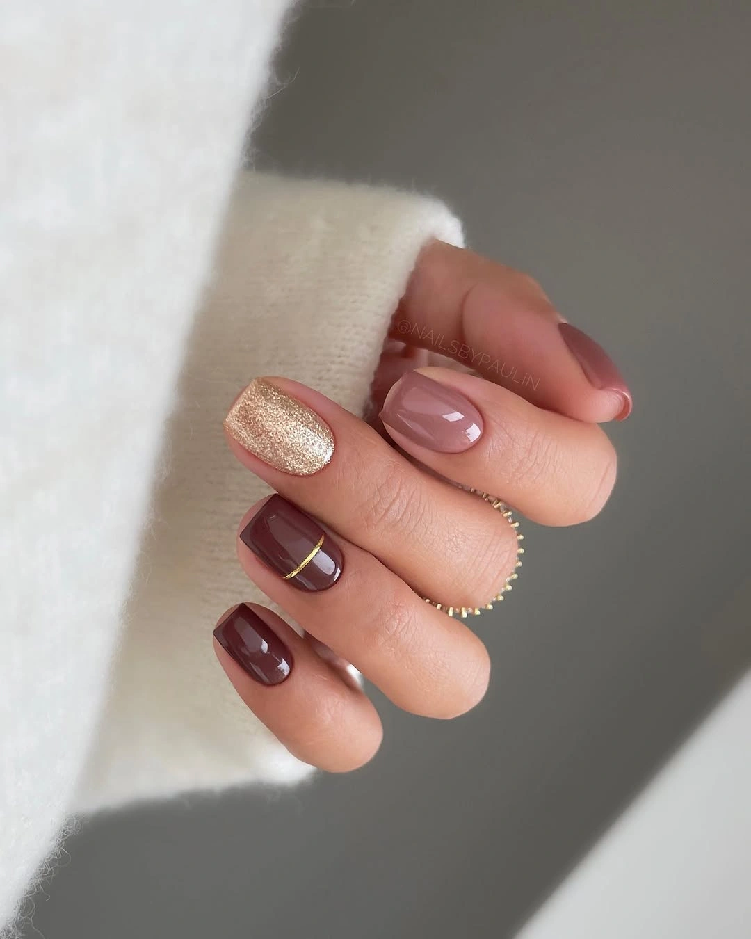 short rounded brown burgundy nails with one gold shimmer accent