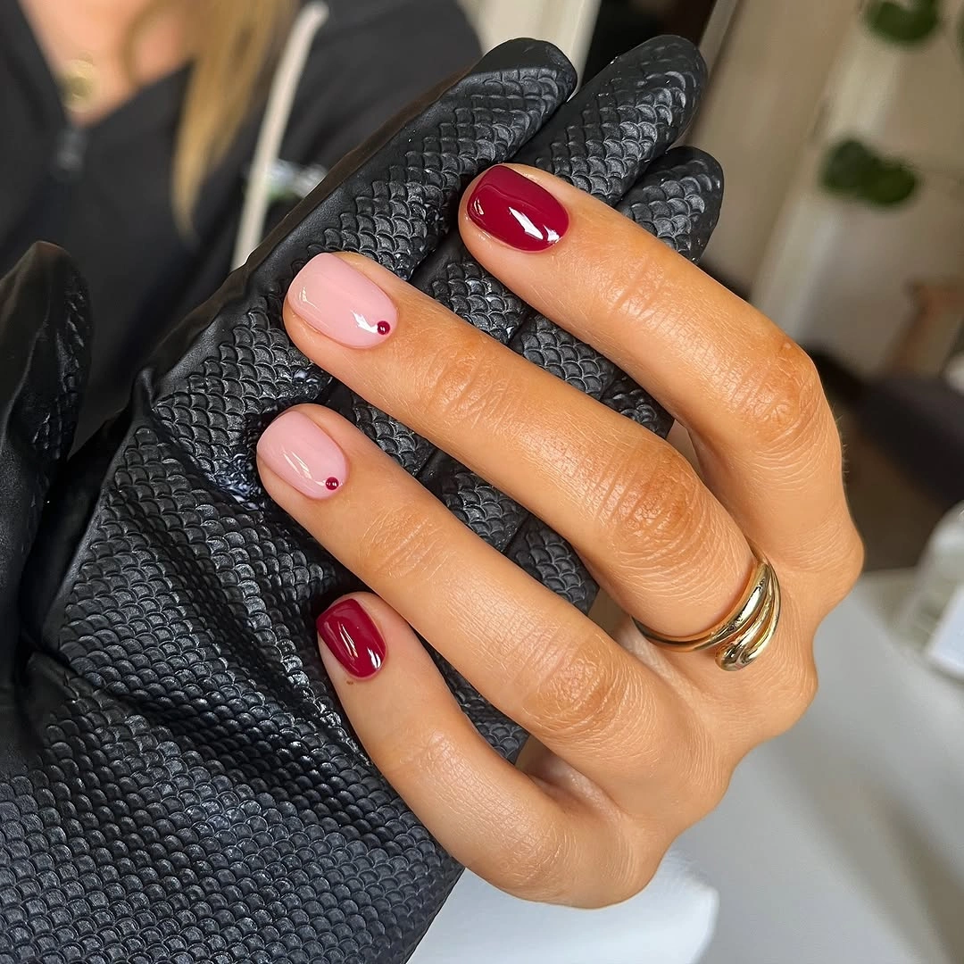 short rounded red and blush nails with tiny edge dots