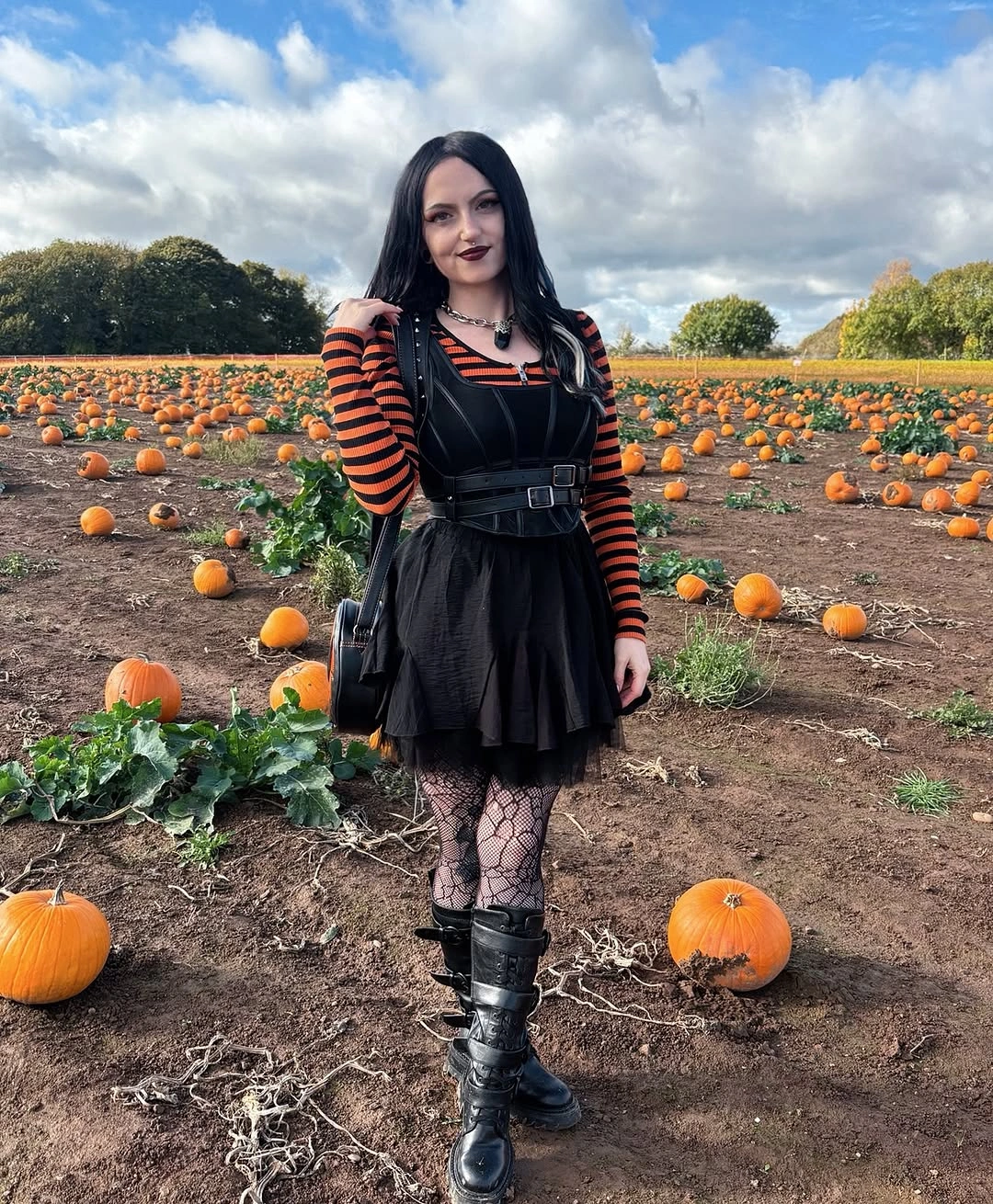 black outfit with short fitted dress with layered sleeves, tights, and tall boots