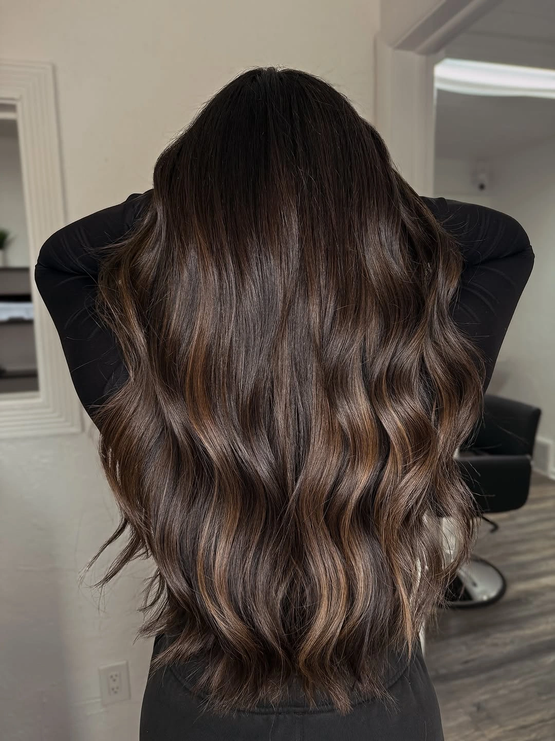 Long dark brunette waves with subtle bronze ribbons through lower lengths
