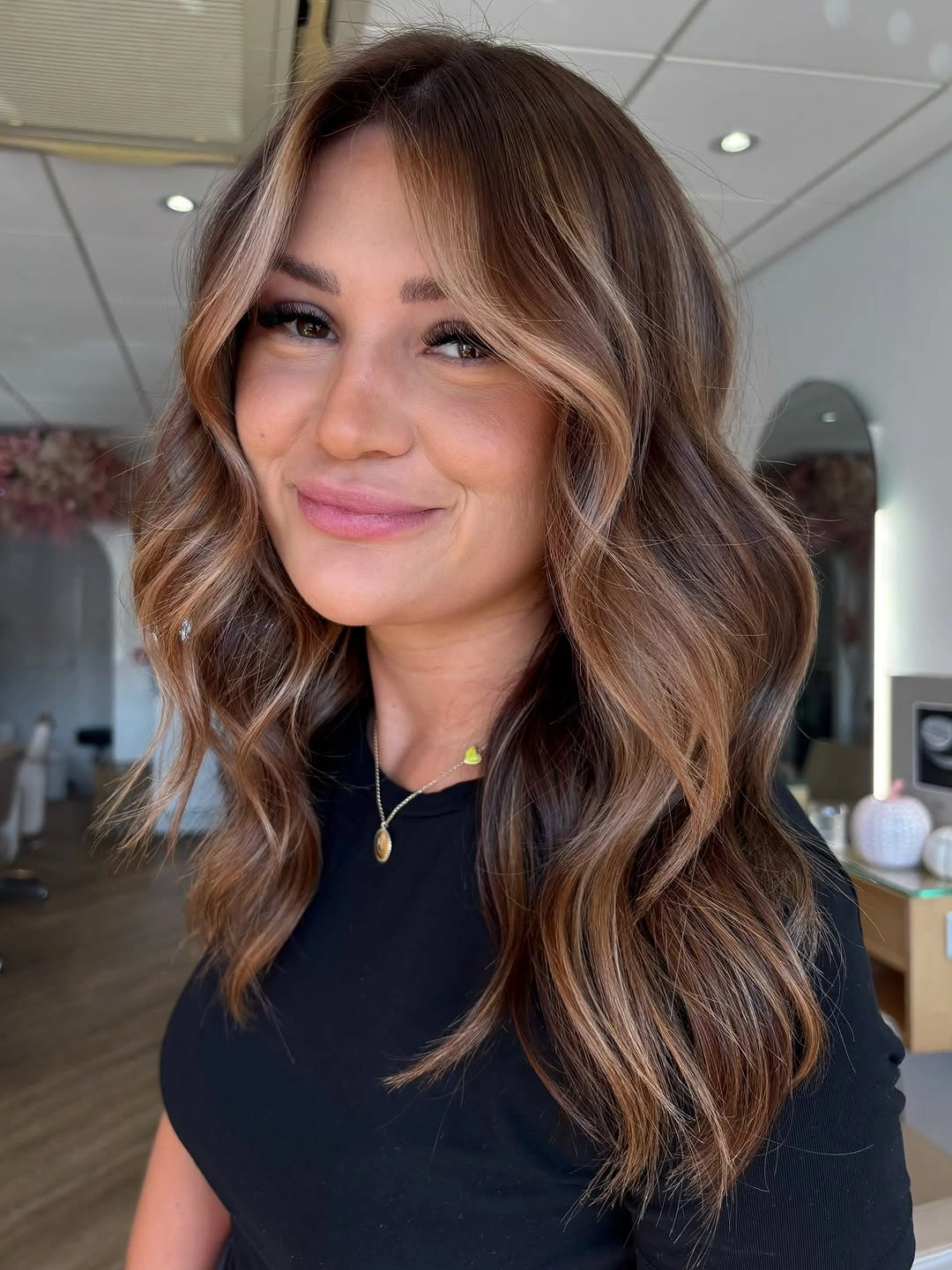 Medium brunette waves with caramel-beige pieces framing the face